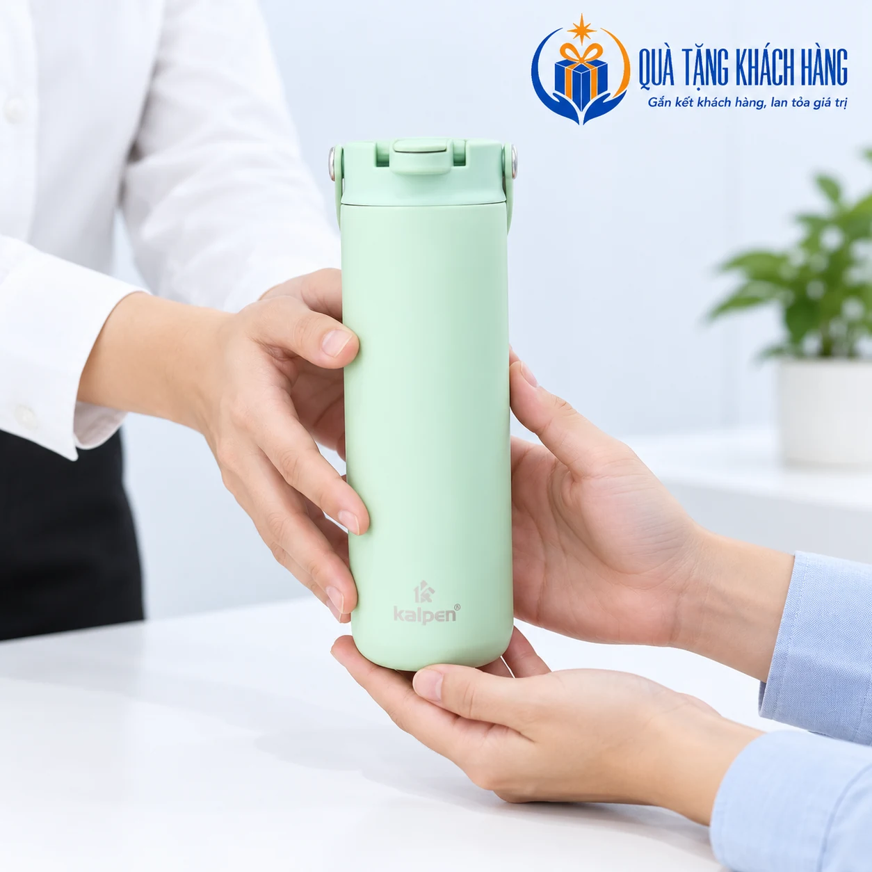 Bàn tay minh họa trao và nhận bình Kalpen DA09 xanh lá tại bàn tiếp khách.