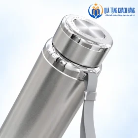Góc nghiêng nắp, cổ kim loại và dây đeo xám của bình Sunhouse Flexi inox.