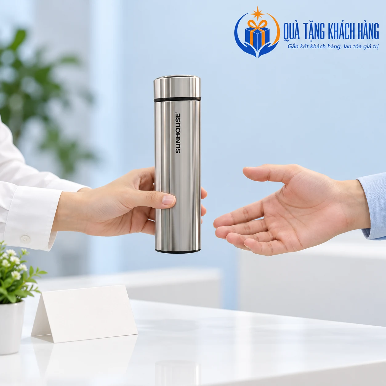 Hai bàn tay minh họa trao và nhận bình Sunhouse KS-TU450 inox bạc ở quầy tiếp khách.