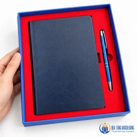 Sổ và bút đặt trong hộp xanh với khay đỏ