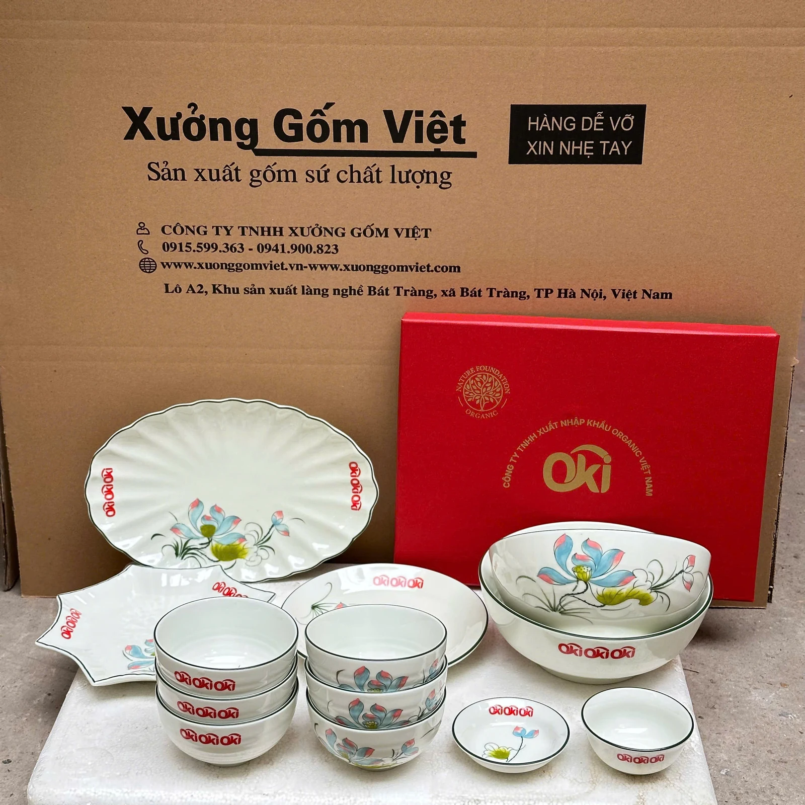 Bộ bát đĩa trắng vẽ hoa có logo đỏ, gồm các dạng đĩa, bát, tô và chén nhỏ.