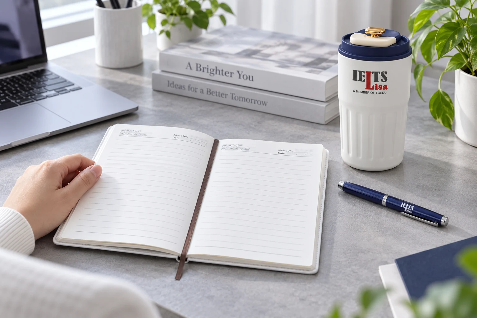 Sổ mở trang kẻ, bút xanh và vật phẩm đồ uống có logo IELTS Lisa trên bàn làm việc minh họa.