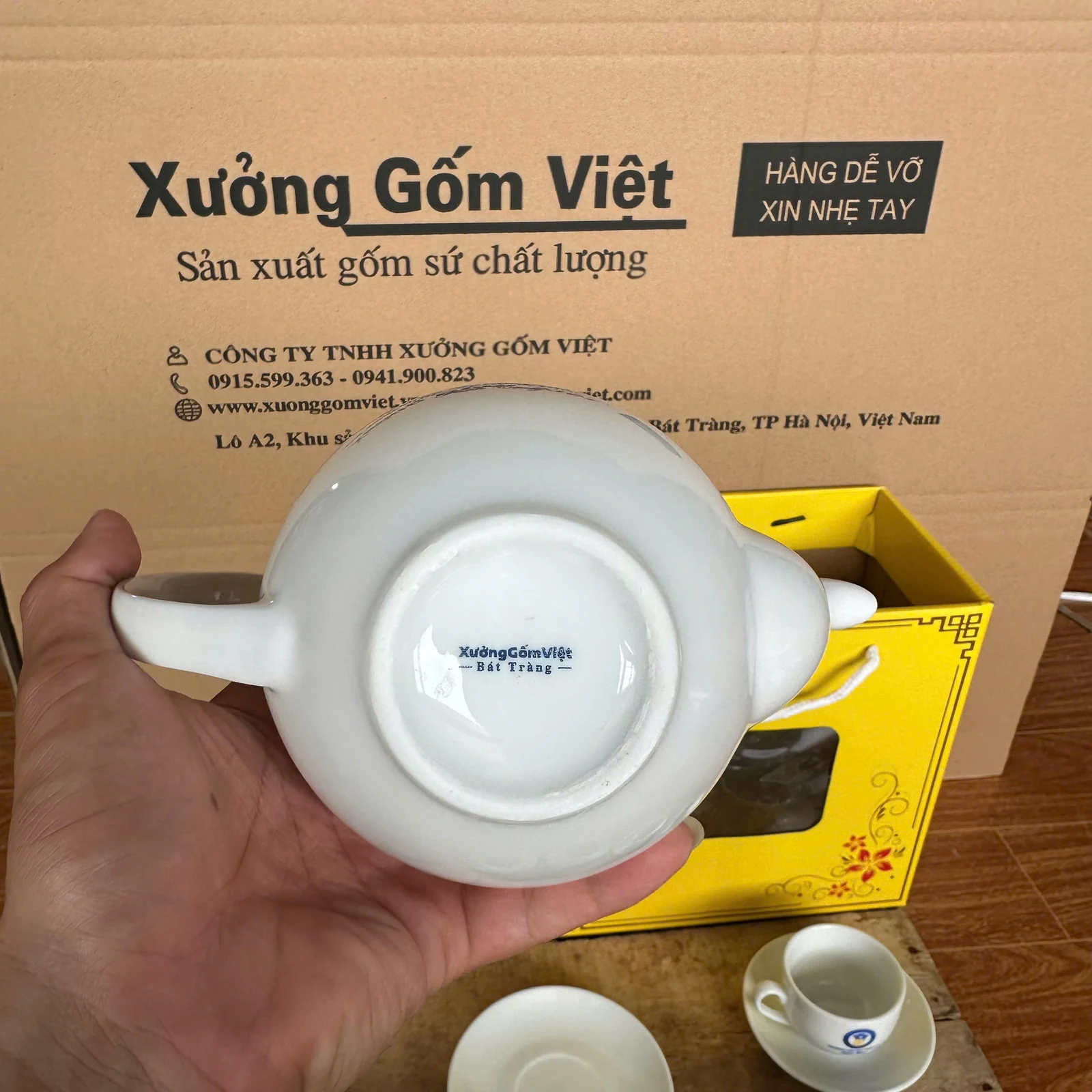 Mặt dưới ấm trắng có dấu Xưởng Gốm Việt trong ảnh nguồn.