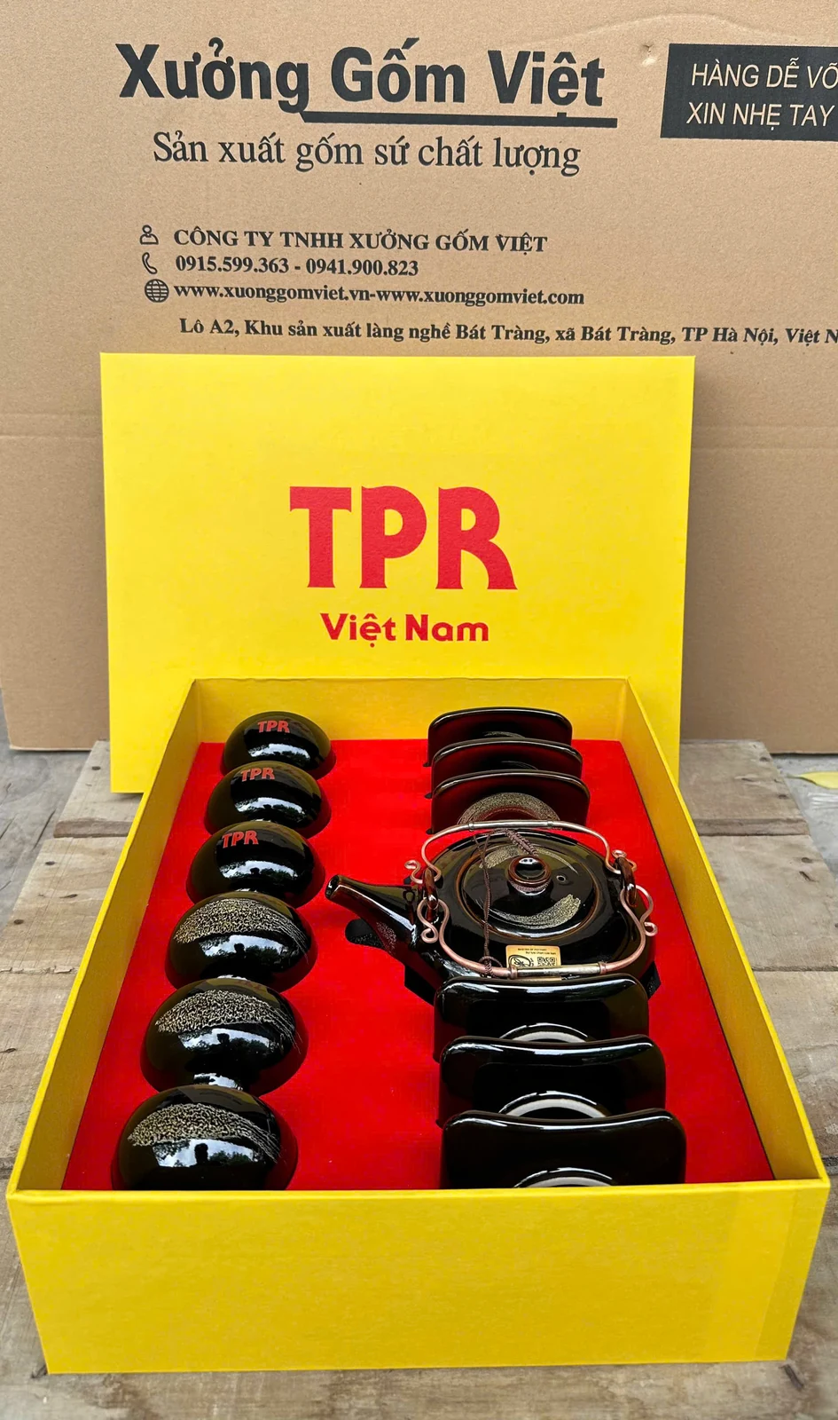Hộp vàng mở nắp, ấm đen và các chén, đĩa được đặt tại những vị trí riêng.