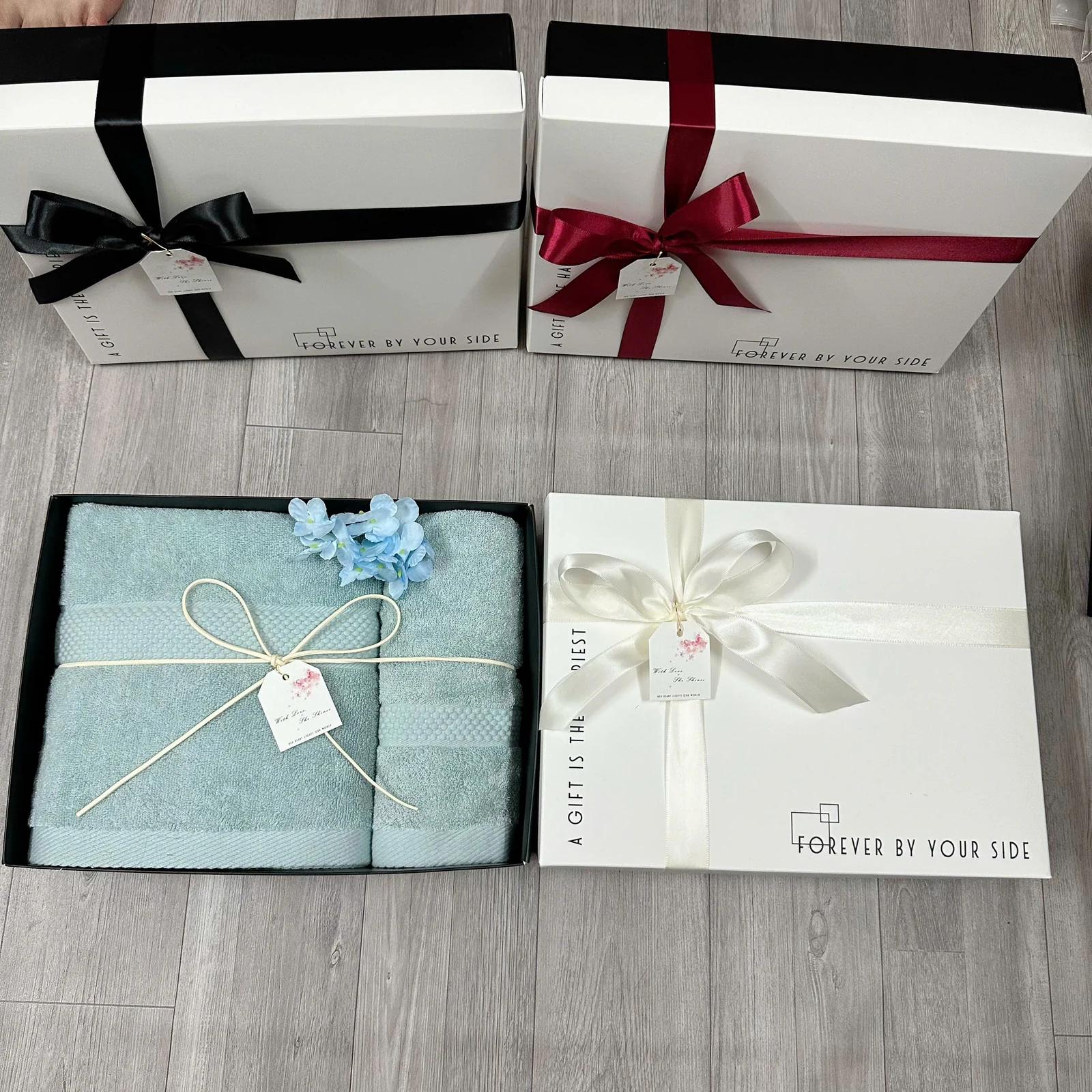 Ảnh thật bộ khăn và các hộp có dây, nơ và thẻ, với cách trình bày khác nhau.