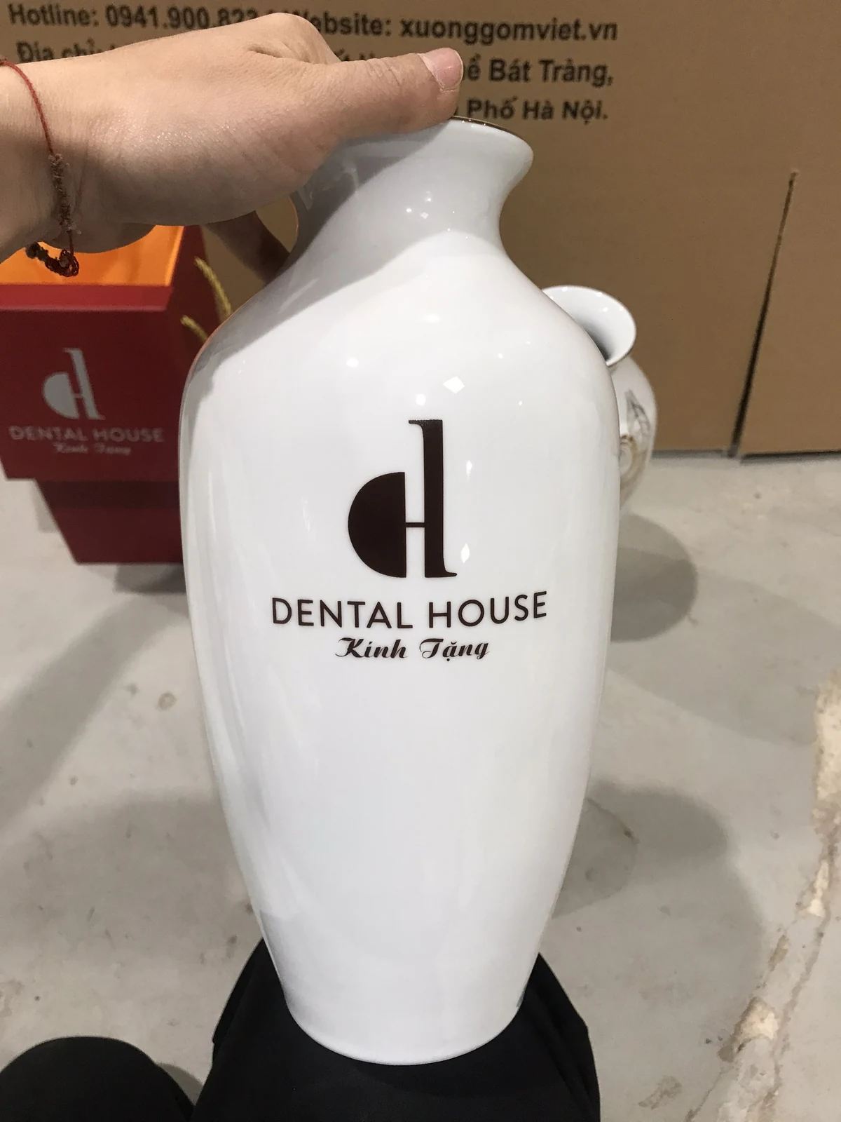 Cận lọ trắng có logo Dental House màu đen và dòng Kính Tặng trong ảnh nguồn.