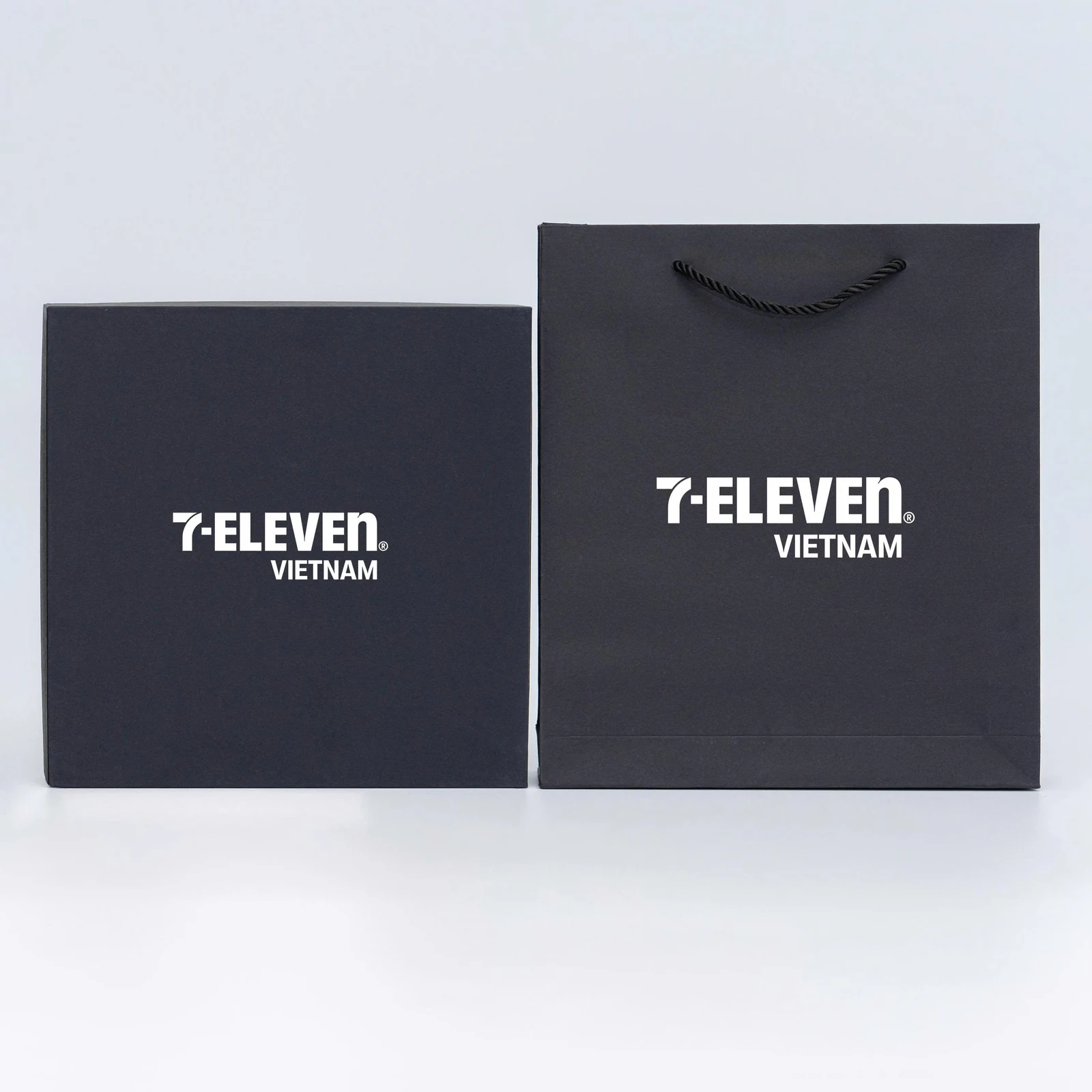 Hộp và túi đen cùng nhận diện 7-Eleven trắng trong ảnh nguồn.