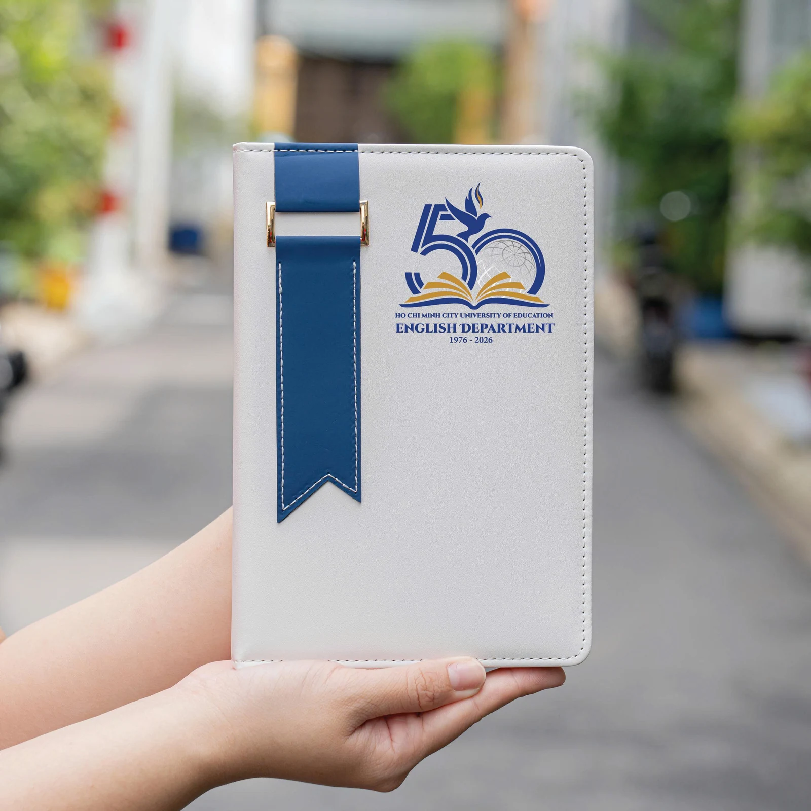 Sổ trắng dải xanh mang nhận diện English Department và mốc kỷ niệm trong ảnh nguồn.