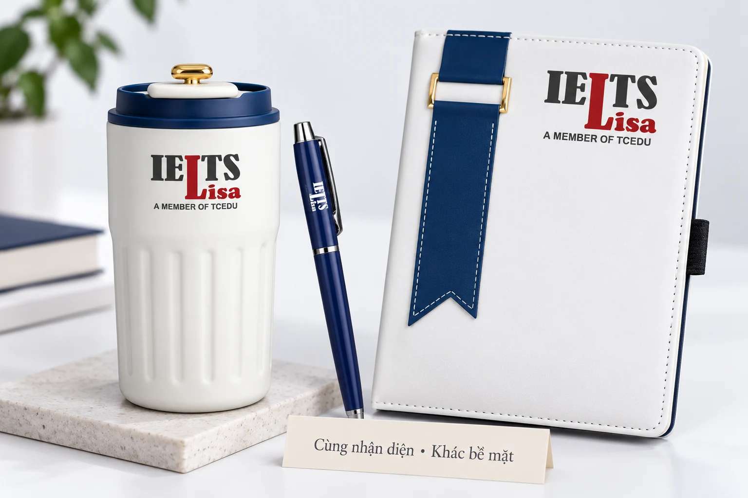 Cận logo IELTS Lisa trên sổ, bút và vật phẩm đồ uống trong ảnh dựng từ mẫu thật.