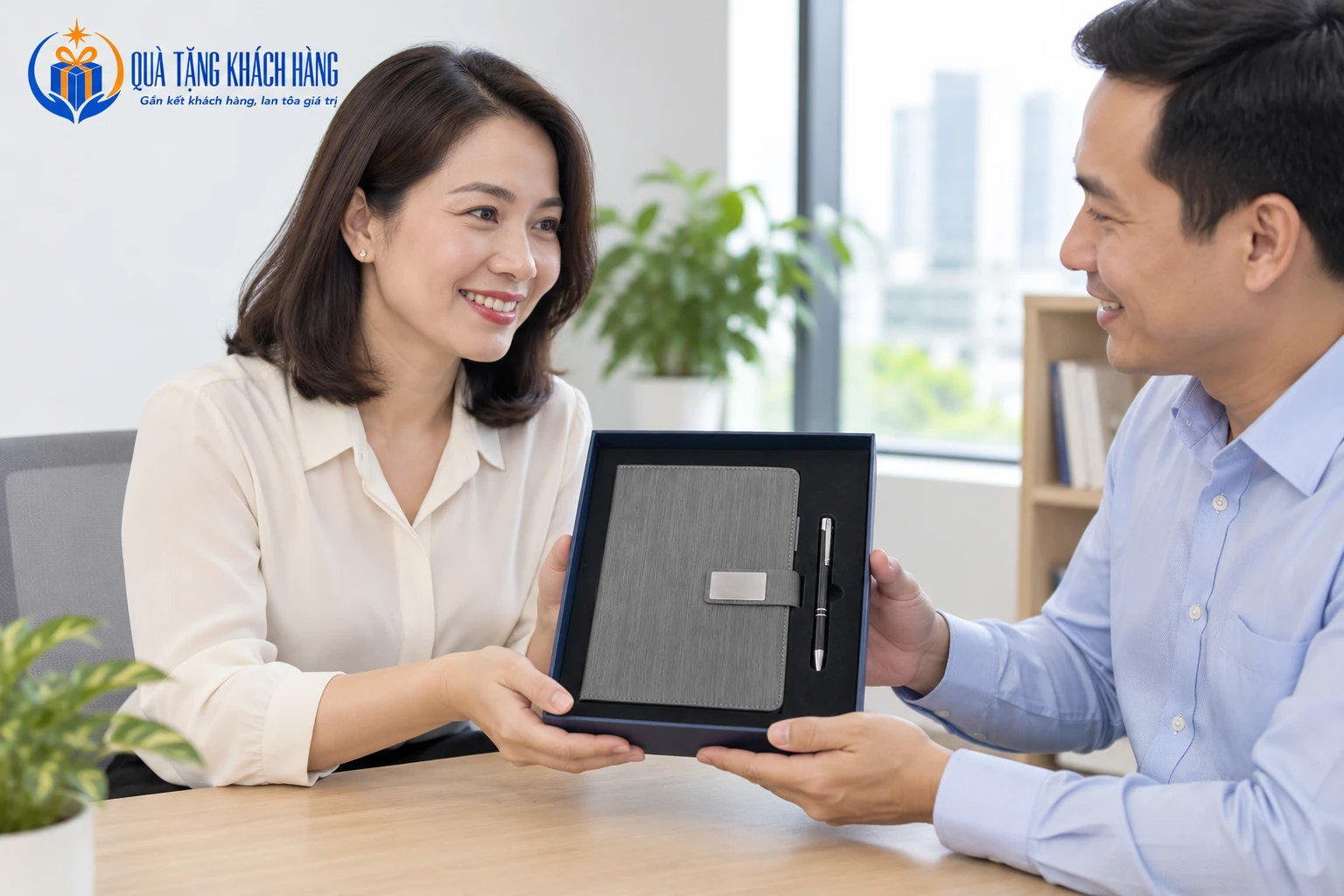 Hai người trao bộ sổ bút xám trong hộp xanh tại một cuộc gặp.