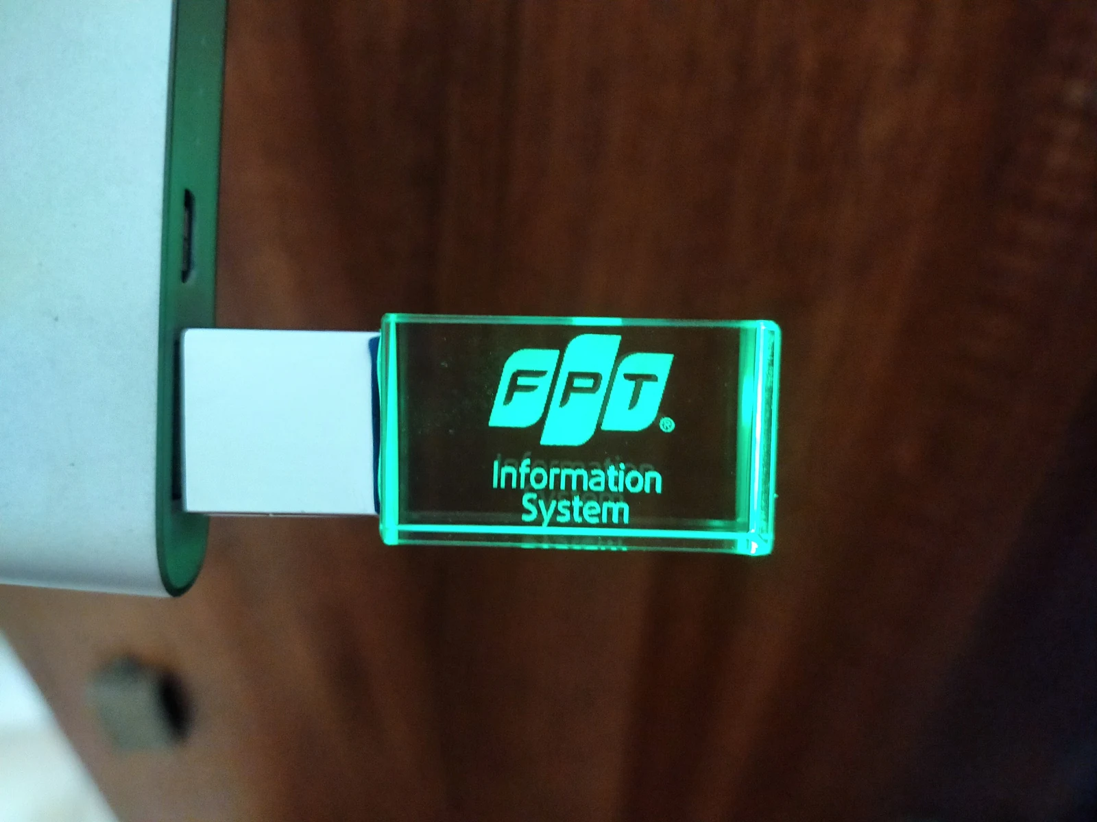 USB có nhận diện FPT Information System phát sáng, được cắm cạnh máy trong ảnh tư liệu.
