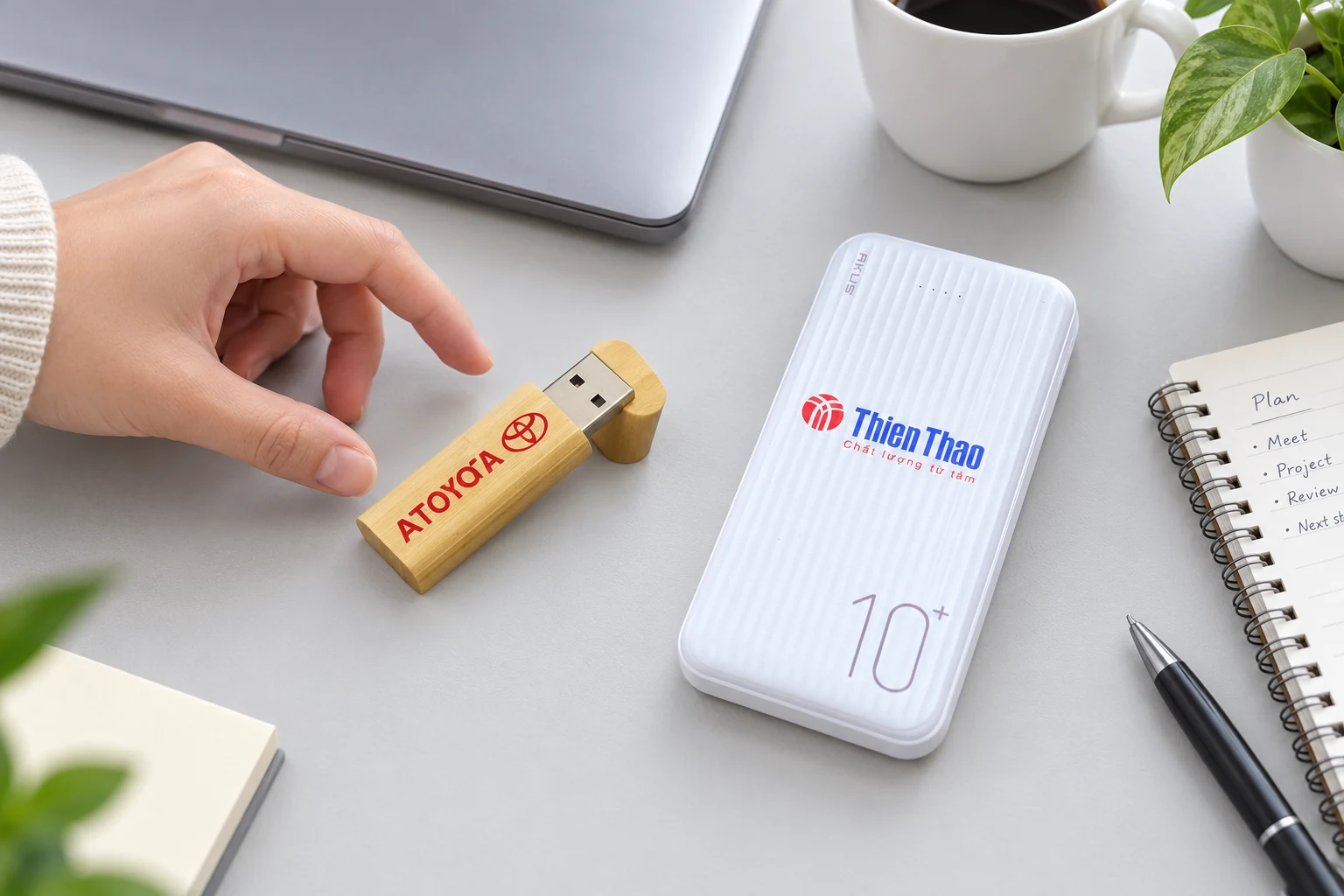 USB vỏ gỗ và sạc dự phòng trắng đặt cạnh laptop trong cảnh làm việc minh họa.